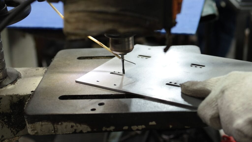 drill press tapping steel sheet metal bracket closeup