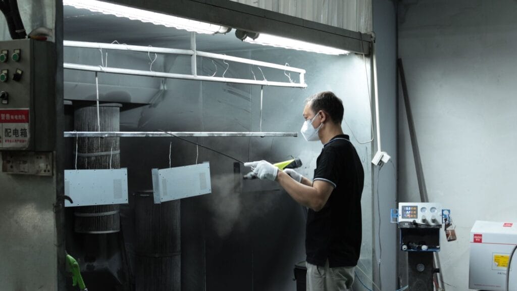 powder coating spray booth worker spraying small panels